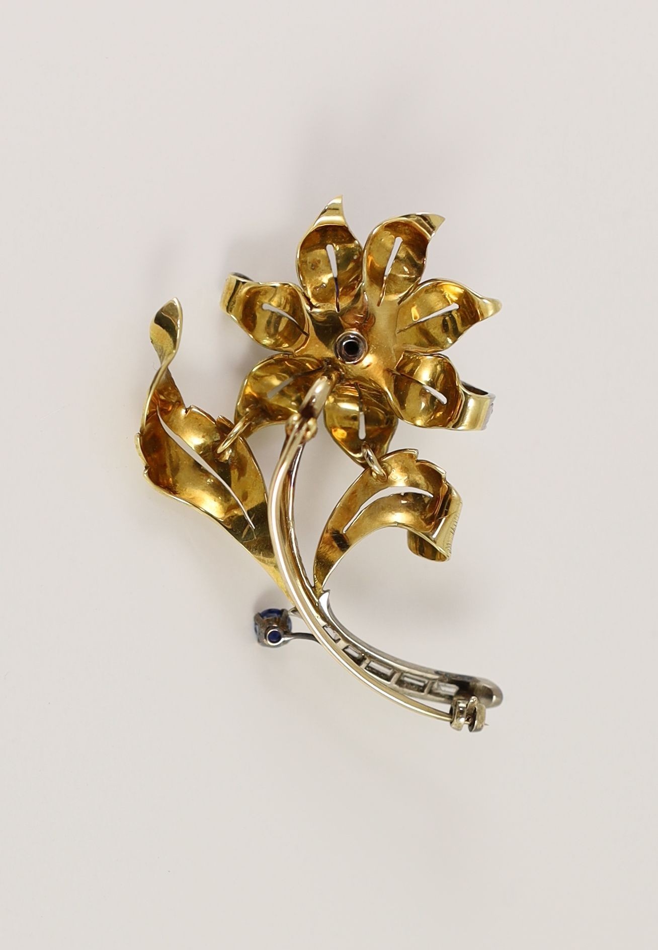 A textured gold, sapphire and diamond floral spray brooch